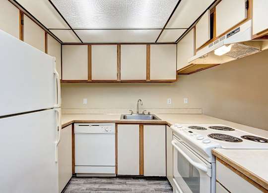 A kitchen with white appliances and wooden cabinets. at Autumn Village, Milton, WA, 98354