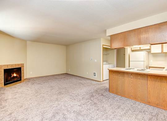 A living room with a fireplace and a kitchen area in the background. at Autumn Village, Washington, 98354