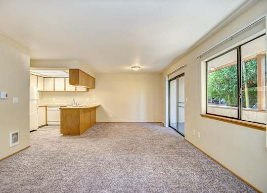 A large, empty room with a kitchen area in the background. at Autumn Village, Milton
