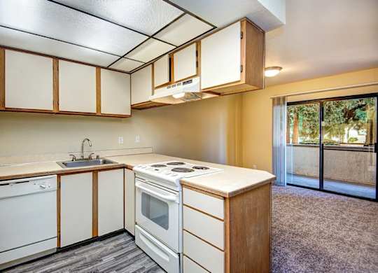 A kitchen with white appliances and wooden cabinets. at Autumn Village, Milton, WA, 98354