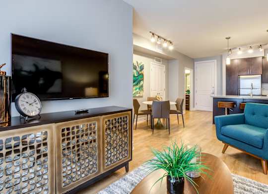 A living room with a television, a blue armchair, and a wooden cabinet.