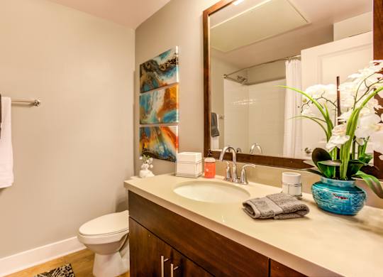 A bathroom with a white toilet and a wooden vanity with a blue vase on it.