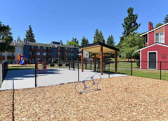 A playground with a basketball hoop and a red building in the background. at Brookstone, SeaTac, WA