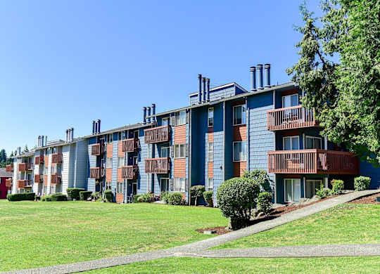 A long building with balconies and a green lawn in front. at Brookstone, SeaTac