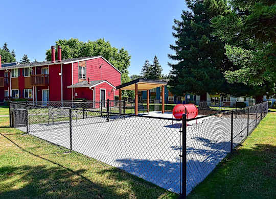 A red building with a black fence and a basketball court in front. at Brookstone, SeaTac, WA