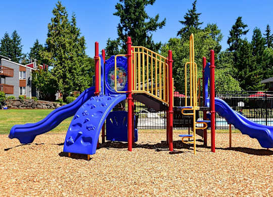A playground with a blue slide and a yellow and red structure. at Brookstone, SeaTac, WA