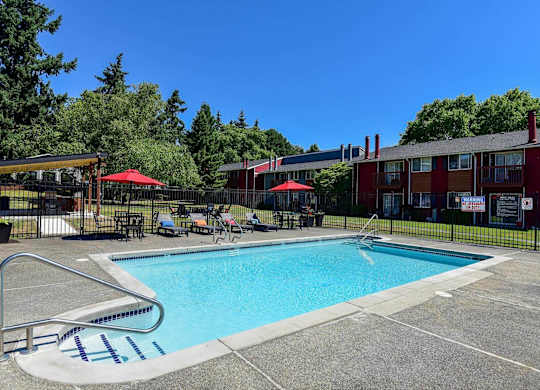 A swimming pool with a slide and a red umbrella. at Brookstone, SeaTac, WA