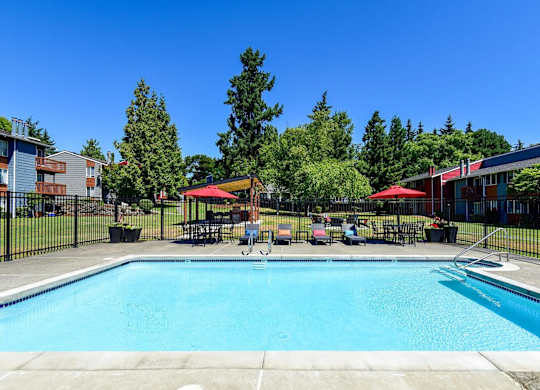 A large swimming pool surrounded by trees and buildings. at Brookstone, SeaTac, WA