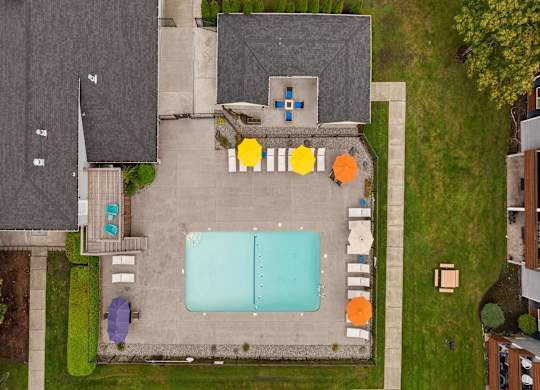 A pool surrounded by a concrete patio and a grassy area. at Northpoint Apartments, Washington