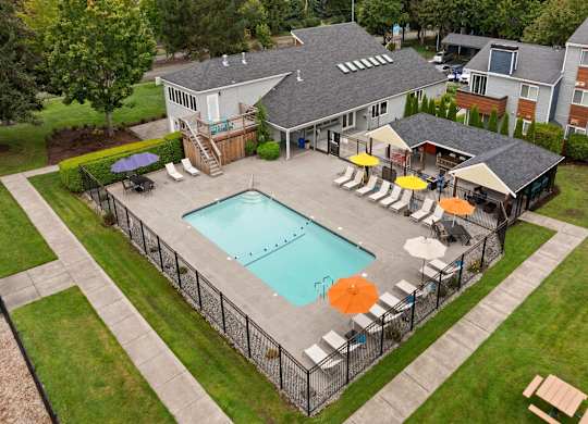 A pool surrounded by a fence and chairs. at Northpoint Apartments, Tacoma