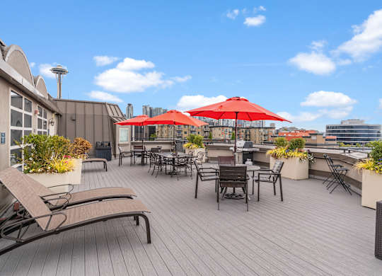 A rooftop patio with red umbrellas and chairs.