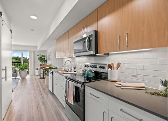 a modern kitchen with white cabinets and stainless steel appliances at Baldwyn, Seattle Washington