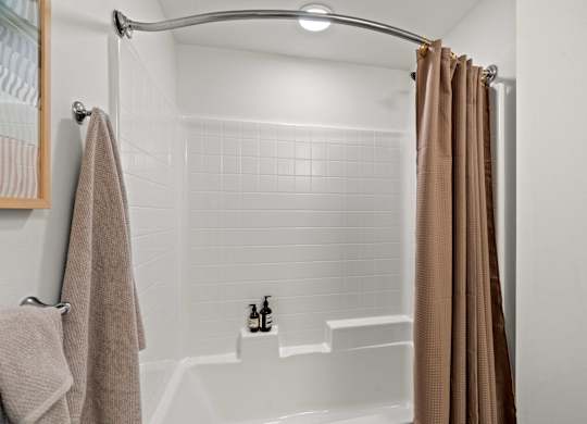 A white shower with white tiles and light brown shower curtain at Baldwyn, Washington, 98125