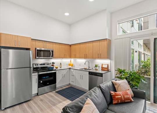 a living room with a couch and a kitchen with stainless steel appliances at Baldwyn, Seattle