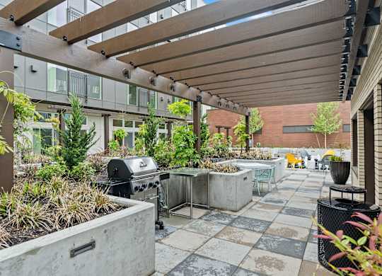 an outdoor patio with a grill and plants at Baldwyn, Seattle, WA 98125