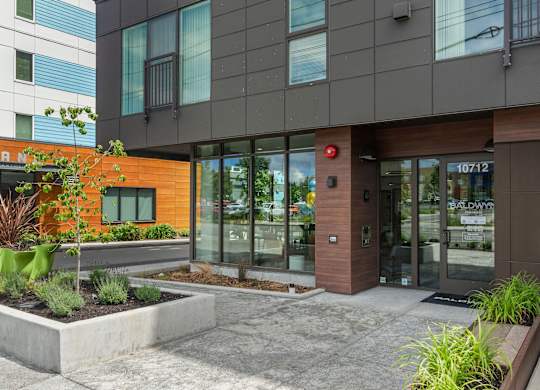 front entrance of a building with glass doors and a sidewalk at Baldwyn, Seattle, WA