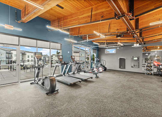 A gym with a variety of equipment including treadmills, weights, and exercise machines.