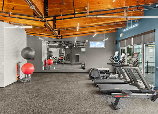 A gym with treadmills, exercise balls, and mirrors.