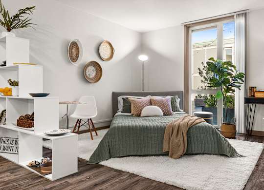 A bedroom with a bed, a desk, and a chair.