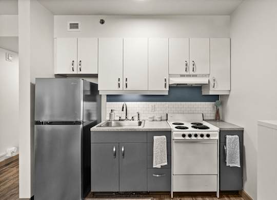 A modern kitchen with a stainless steel refrigerator and white cabinets.