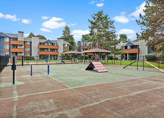A playground with a red slide and a basketball hoop. at Northpoint Apartments, Tacoma, Washington