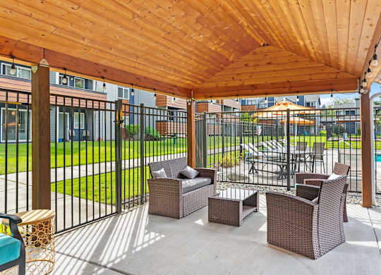 A patio with a wooden roof and wicker furniture. at Northpoint Apartments, Tacoma