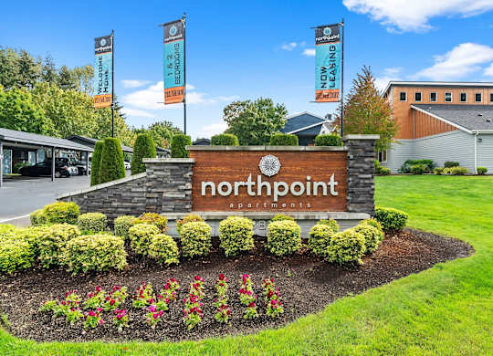 A sign for Northpoint Apartments is surrounded by flowers and greenery. at Northpoint Apartments, Tacoma, Washington