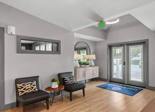 A waiting area with two black chairs and a wooden table. at Northpoint Apartments, Washington