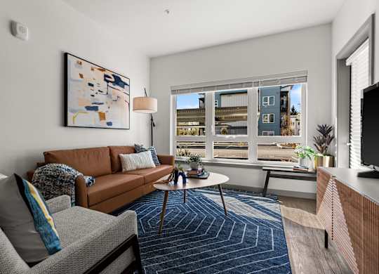 a living room with a large window and a brown couch at Gage On Sixth, Tacoma