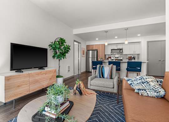 a living room with a tv and a kitchen in the background at Gage On Sixth, Tacoma