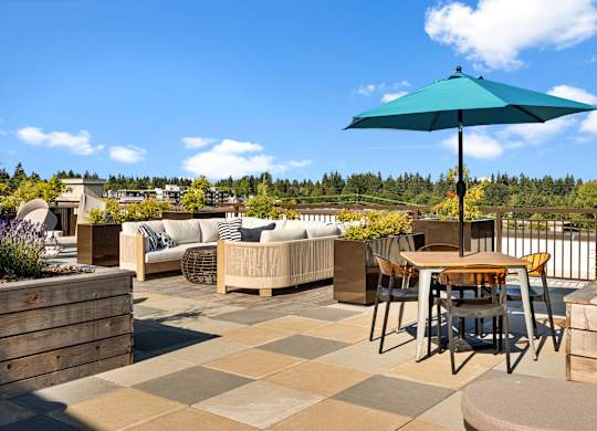 a rooftop patio with tables and chairs and an umbrella at Baldwyn, Seattle, 98125