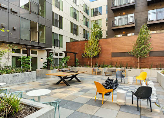 an outdoor patio with tables and chairs in front of an apartment building at Baldwyn, Seattle, WA 98125