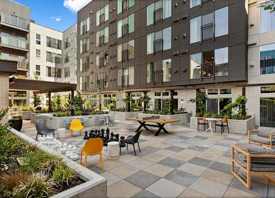 an open courtyard with tables and chairs in front of an apartment building at Baldwyn, Seattle, 98125