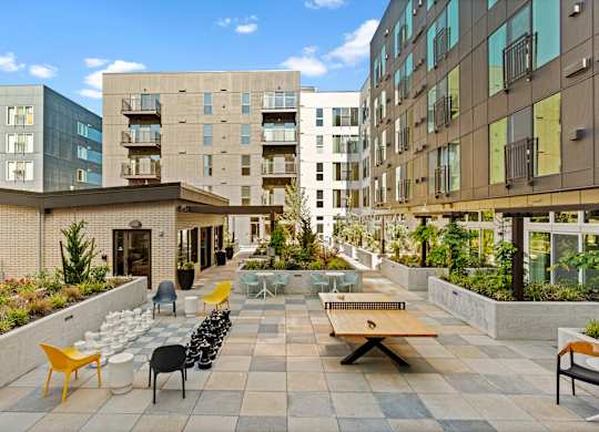 an outdoor patio with tables and chairs and buildings in the background at Baldwyn, Seattle, WA