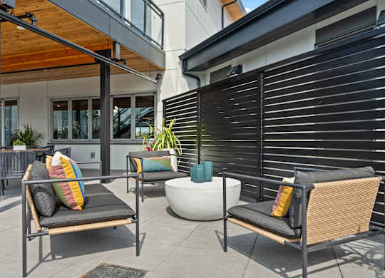 a patio with chairs and a table and a building in the background at Gage On Sixth, Tacoma, WA, 98465