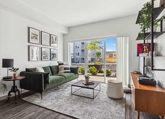 a living room with a green couch and a large window at Gage On Sixth, Washington, 98465