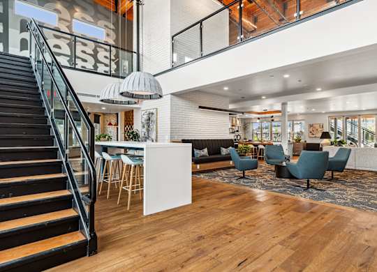 a living room with a staircase and a lobby with chairs and tables at Gage On Sixth, Tacoma, WA, 98465