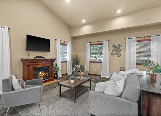A living room with a fireplace and a grey couch.