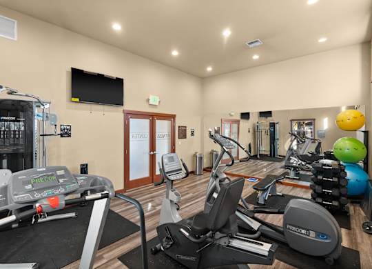 A gym with a variety of exercise equipment including treadmills, stationary bikes, and weight machines.