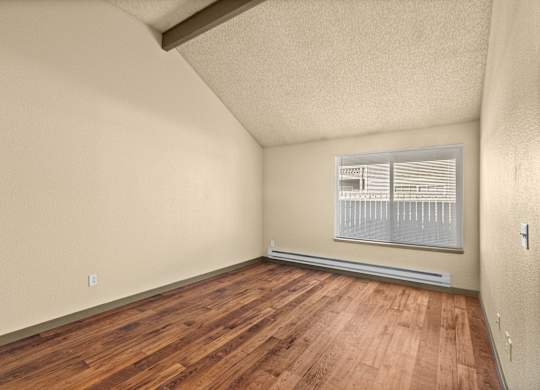 Empty room with wooden flooring and a window.