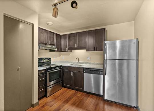 A kitchen with a refrigerator, sink, and oven.