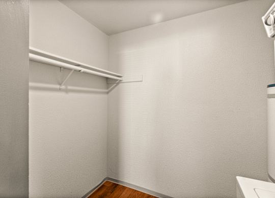 A white closet with a shelf and a white door.
