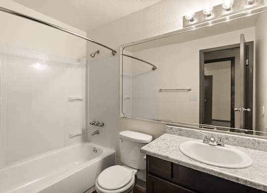 A white toilet sits next to a white bathtub in a bathroom.