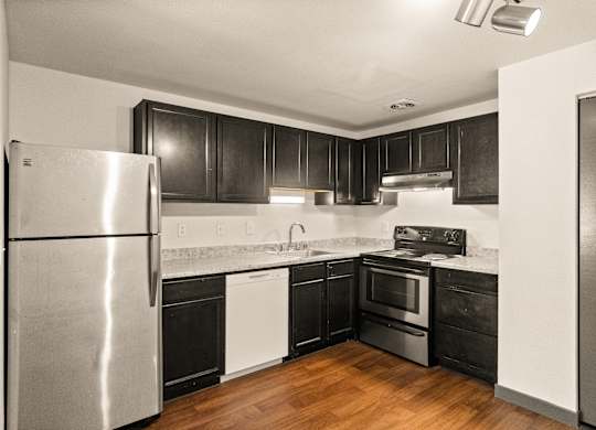 A modern kitchen with a stainless steel refrigerator and black cabinets.