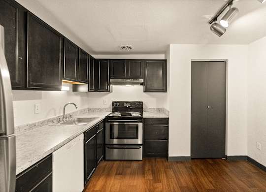 A kitchen with black cabinets and a stainless steel refrigerator.