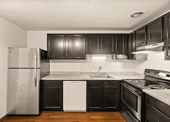 A kitchen with black cabinets and a stainless steel refrigerator.