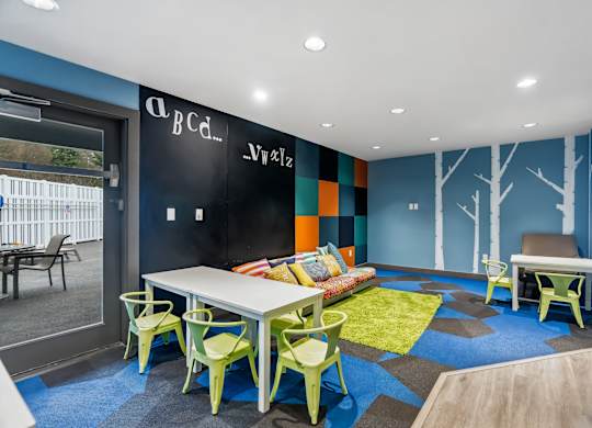 A room with a white table and green chairs.