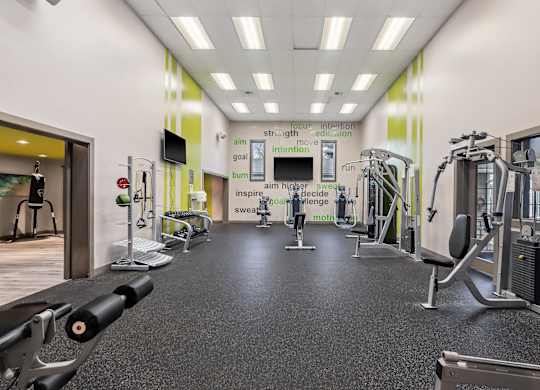 A gym with a variety of equipment including treadmills, weights, and exercise machines.
