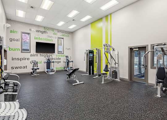 A gym with a variety of equipment and motivational words on the wall.