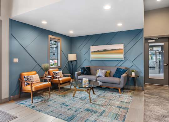 A living room with a blue wall and a painting of a beach scene.